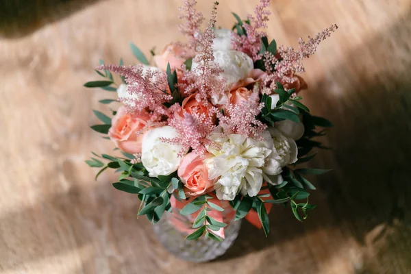 ช่อดอกไม้แต่งงานของดอกโบตั๋นสีขาวและกุหลาบสีชมพูโต๊ะไม้ ความเขียวขจีมากมาย พวงเจ้าสาวที่ไม่สมมาตรสมัยใหม่ — ภาพถ่ายสต็อก