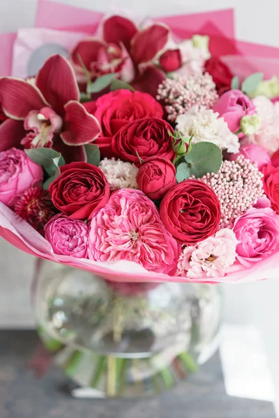 Leuchtend roter Strauß schöner Blumen auf dem Holztisch. Floristikkonzept. Frühlingsfarben. die Arbeit des Blumenhändlers in einem Blumenladen. vertikales Foto — Stockfoto