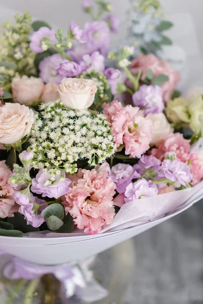 Strauß schöner Blumen auf grauem Tisch. Floristikkonzept. Frühlingsfarben. die Arbeit des Blumenhändlers in einem Blumenladen. vertikales Foto — Stockfoto