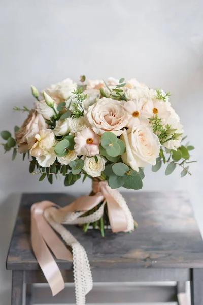 Hochzeitsstrauß aus weißen Rosen und Butterblume auf einem Holztisch. Viel Grün, moderner asymmetrisch zerzauster Brautstrauß — Stockfoto