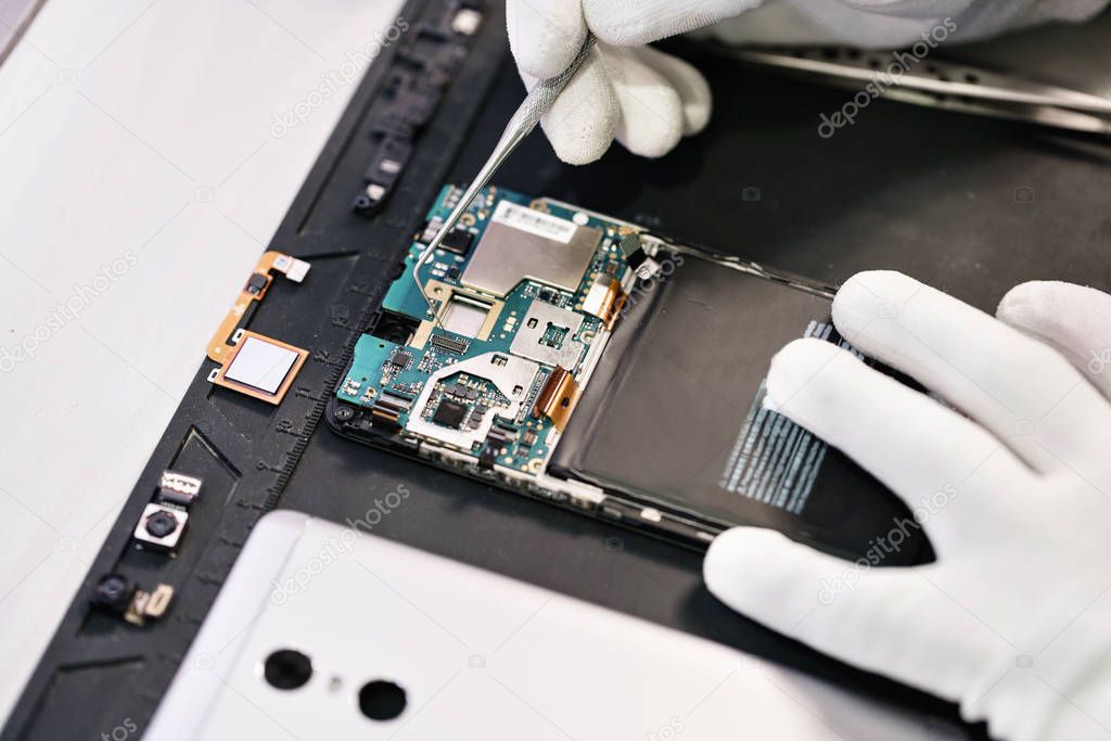 Work with a microscope. Microelectronics device. Close-up hands of a service worker repairing modern smartphone. Repair and service concept.