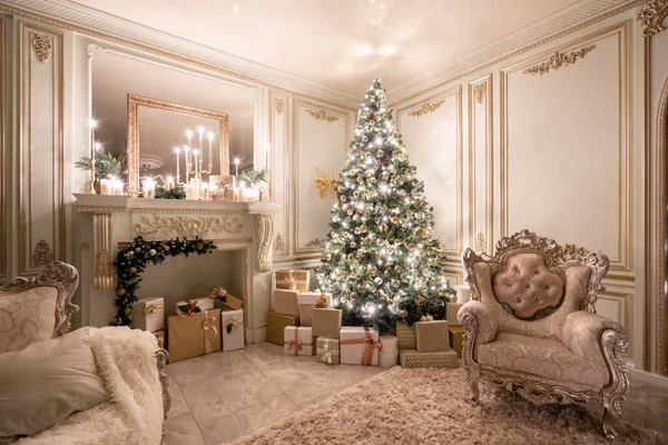 Heiligabend im Schein von Kerzen und Girlanden. klassische luxuriöse Apartments mit geschmücktem Weihnachtsbaum und Geschenken. Wohnen mit Kamin, Säulen und Stuck. — Stockfoto