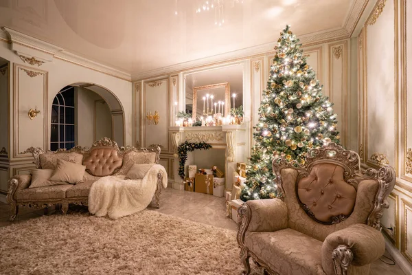 Christmas evening in the light of candles and garlands. Classic luxurious apartments with decorated christmas tree and presents. Living with fireplace, columns and stucco. — Stock Photo, Image