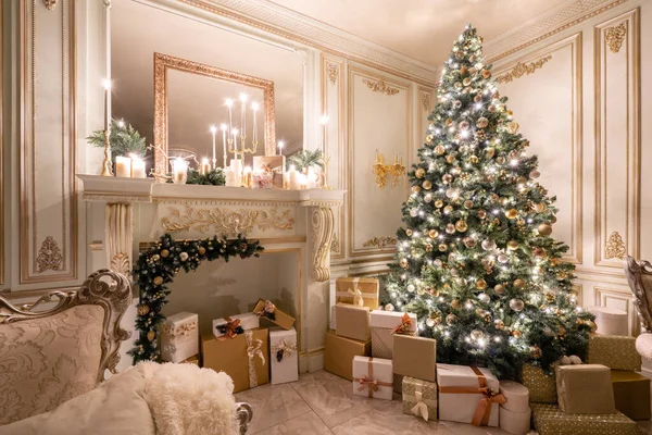 Noite de Natal à luz de velas e guirlandas. Apartamentos clássicos de luxo com árvore de natal decorada e presentes. Viver com lareira, colunas e estuque . — Fotografia de Stock