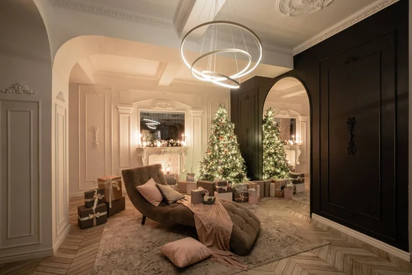 Noche de Navidad a la luz de velas y guirnaldas. Apartamentos de lujo clásicos con árbol de Navidad decorado y regalos. Vivir con chimenea, columnas y estuco . — Foto de Stock