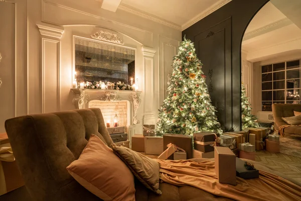 Noite de Natal à luz de velas e guirlandas. Apartamentos clássicos de luxo com árvore de natal decorada e presentes. Viver com lareira, colunas e estuque . — Fotografia de Stock