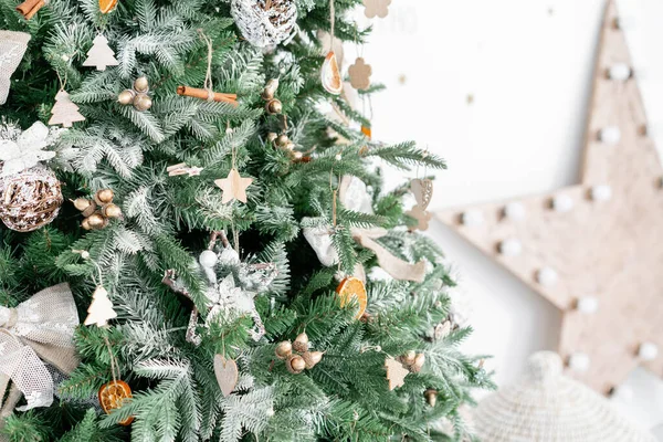 Κοντινά κλαδιά χριστουγεννιάτικου δέντρου με στολίδια. Χριστουγεννιάτικες μπάλες, φιόγκο κορδέλας, νιφάδες χιονιού, κουκουνάρια και φώτα. — Φωτογραφία Αρχείου