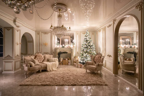 Christmas evening in the light of candles and garlands. Classic luxurious apartments with decorated christmas tree and presents. Living with fireplace, columns and stucco. — Stock Photo, Image