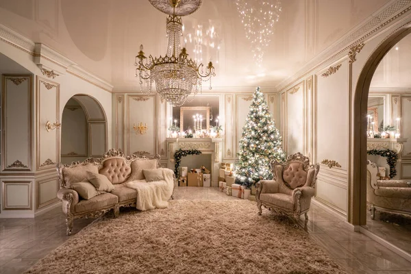 Christmas evening in the light of candles and garlands. Classic luxurious apartments with decorated christmas tree and presents. Living with fireplace, columns and stucco. — Stock Photo, Image