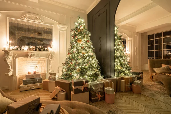 Christmas evening in the light of candles and garlands. Classic luxurious apartments with decorated christmas tree and presents. Living with fireplace, columns and stucco.