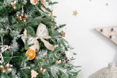 Noel ağacının süslemeli dalları. Noel baloları, kurdele yayı, kar taneleri, çam kozalakları ve ışıklar.