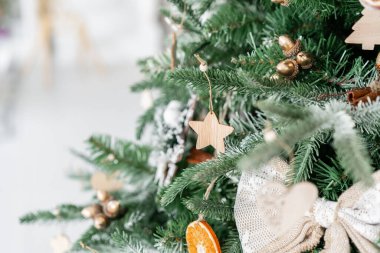 Noel ağacının süslemeli dalları. Noel baloları, kurdele yayı, kar taneleri, çam kozalakları ve ışıklar.
