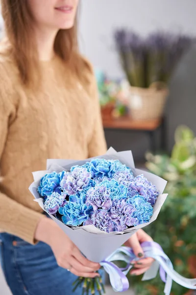 Mono bouquet of blue carnations in woman hand. Unusual flowers dianthus . Spring flower pattern