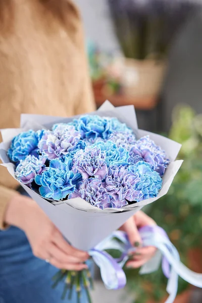 Mono bouquet of blue carnations in woman hand. Unusual flowers dianthus . Spring flower pattern