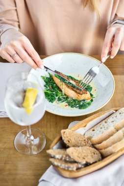Tahıllı hardal ve ıspanaklı somon bifteği fileto. Bir restoranda öğle yemeği, bir kadın lezzetli ve sağlıklı yiyecekler yer. Restoran menüsü, bir dizi farklı yemeğin fotoğrafları.