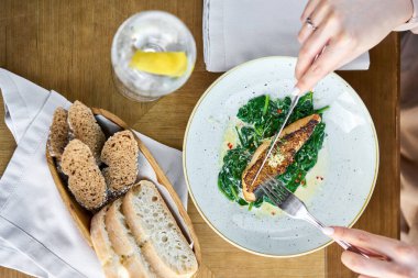 Tahıllı hardal ve ıspanaklı somon bifteği fileto. Bir restoranda öğle yemeği, bir kadın lezzetli ve sağlıklı yiyecekler yer. Restoran menüsü, bir dizi farklı yemeğin fotoğrafları.