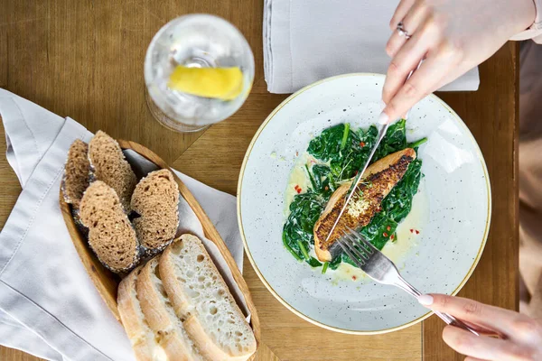 Tahıllı hardal ve ıspanaklı somon bifteği fileto. Bir restoranda öğle yemeği, bir kadın lezzetli ve sağlıklı yiyecekler yer. Restoran menüsü, bir dizi farklı yemeğin fotoğrafları.