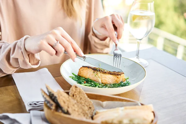 Salmon steak fillet with grainy mustard and spinach. Lunch in a restaurant, a woman eats delicious and healthy food. Restaurant menu, a series of photos of different dishes — Stock Photo, Image