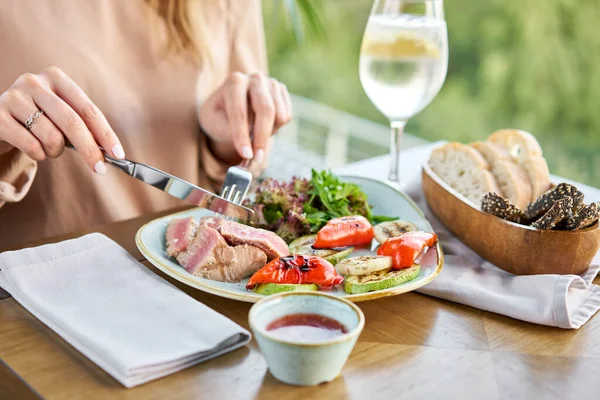 Déjeuner dans un restaurant, une femme mange du thon moyen rare avec de la laitue et de la sauce piquante. Menu restaurant — Photo