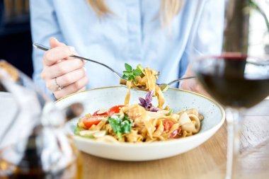 Kadın deniz ürünleri ve domates soslu İtalyan makarnayiyor. Makarna Gamberini. Yakın çekim tagliatelle bir kaşıkla bir çatal etrafında rüzgar. Parmesan peyniri
