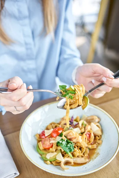 La mujer come pasta italiana con mariscos y salsa de tomate. Pasta Gamberini. Close-up tagliatelle enrollarlo alrededor de un tenedor con una cuchara. Queso parmesano — Foto de Stock