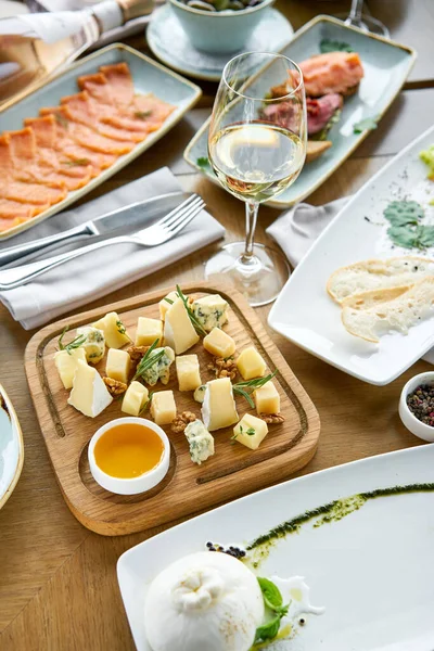 Cheese plate. Focus on delicious cheese mix with walnuts, honey on wooden table. Various snacks and antipasti on the table. Restaurant menu. — Stock Photo, Image