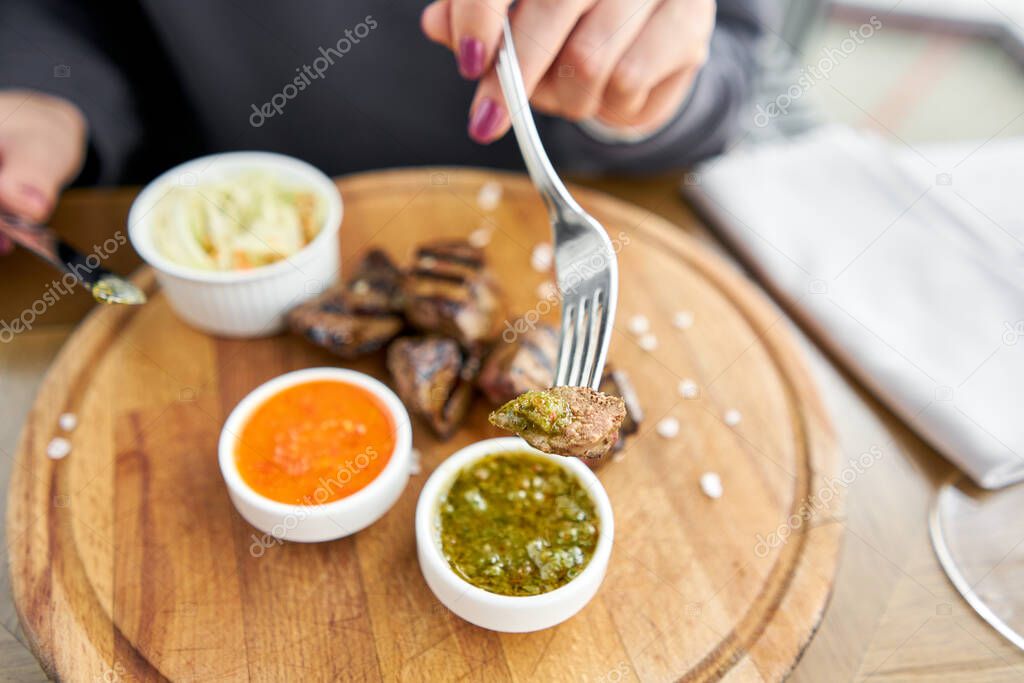 Lunch in a restaurant, a woman eats Pieces of liver cooked on the grill. Serving on a wooden Board. Barbecue restaurant menu, a series of photos of different meats.