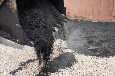 Bir traktör asfaltı boşaltıyor. Büyük ağır makineler yol onarımı yapıyor. Yeni asfalt seriyorum. Yeni bir asfalt yol inşaatı.