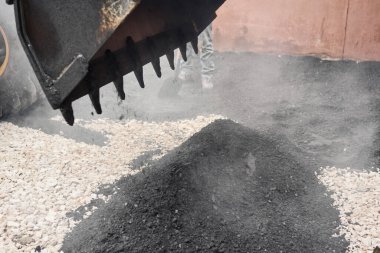 Bir traktör asfaltı boşaltıyor. Büyük ağır makineler yol onarımı yapıyor. Yeni asfalt seriyorum. Yeni bir asfalt yol inşaatı.