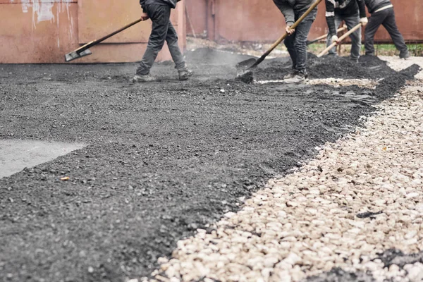 Colocando asfalto nuevo, cubriendo la fosa, sobre los escombros. Los trabajadores llevan palas y usan laúd de asfalto para asfalto suave y caliente . — Foto de Stock