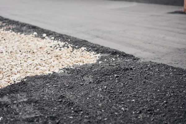 Primer plano nuevo asfalto caliente. Colocando asfalto, cubriendo la fosa, sobre los escombros. Asfalto Compactadores está llevando a cabo trabajos de reparación de carreteras . — Foto de Stock