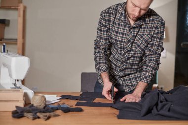 Terzi yün kesim kumaşı. Çizgi deseni. El sanatları ustası yün kumaştan papyonlar için dikdörtgen boşluklar yapıyor. Tekstil atölyesinde dikiş makinesiyle çalışıyorum..