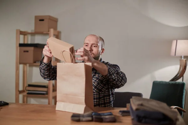 Mannen packar ullfluga i en låda. Ung man som arbetar som skräddare och använder symaskin i verkstad. — Stockfoto