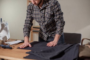 Terzi yün kesim kumaşı. Çizgi deseni. El sanatları ustası yün kumaştan papyonlar için dikdörtgen boşluklar yapıyor. Tekstil atölyesinde dikiş makinesiyle çalışıyorum..