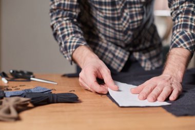 Terzi yün kesim kumaşı. Çizgi deseni. El sanatları ustası yün kumaştan papyonlar için dikdörtgen boşluklar yapıyor. Tekstil atölyesinde dikiş makinesiyle çalışıyorum..