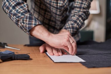 Terzi yün kesim kumaşı. Çizgi deseni. El sanatları ustası yün kumaştan papyonlar için dikdörtgen boşluklar yapıyor. Tekstil atölyesinde dikiş makinesiyle çalışıyorum..