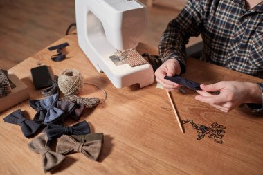 Terzi yün kumaştan papyon yapar. Tekstil atölyesinde dikiş makinesiyle çalışıyorum..