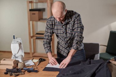Terzi yün kesim kumaşı. Çizgi deseni. El sanatları ustası yün kumaştan papyonlar için dikdörtgen boşluklar yapıyor. Tekstil atölyesinde dikiş makinesiyle çalışıyorum..