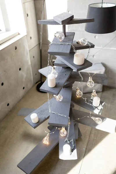Alternativer hölzerner Weihnachtsbaum. ein handgemachter Weihnachtsbaum und eine Glühbirne auf dem Fußboden im Zimmer — Stockfoto