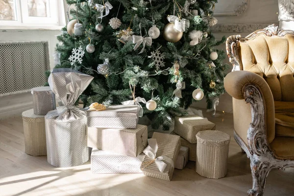 Muchos regalos de Navidad bajo el árbol con adornos. Bolas de Navidad, lazo de cinta, copos de nieve, piñas y luces . — Foto de Stock