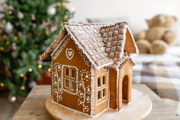 Gingerbread house, concept holiday of Christmas and Happy new year. Defocused lights of Christmas tree. Morning in the bright living room. Holiday mood.