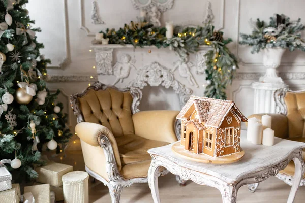 Gingerbread house, concept holiday of Christmas and Happy new year. Defocused lights of Christmas tree. Morning in the bright living room. Holiday mood.