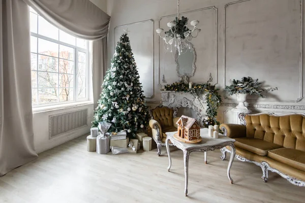 Boże Narodzenie rano. Klasyczne luksusowe apartamenty z białym kominkiem, choinką, sofą, dużymi oknami i żyrandolem. — Zdjęcie stockowe