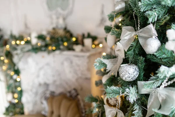 Karácsonyfa ágak közelsége dekoratív labdákkal, szalagíjakkal, hópelyhekkel, fenyőtobozokkal és fényekkel. — Stock Fotó