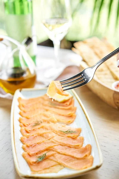 叉子上的咸鱼和熏鱼片或鳟鱼片的堵塞。 薄片红鱼,柠檬近身. 餐厅菜单 — 图库照片