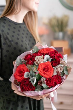 Karışık kırmızı ton buketi. Kadınların elinde bir demet taze çiçek. Çiçekçi dükkanındaki çiçekçinin işi. Taze kesilmiş çiçek..