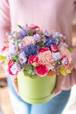 Avrupa çiçekçisi. Yuvarlak kutuda çiçek demeti. Bir buket güzel Karışık çiçek kadının elinde. Mükemmel bahçe çiçekleri. Profesyonel bir çiçekçinin işi..