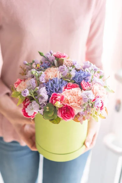 Tienda floral europea. Ramo floral en caja redonda. Ramo de hermosas flores mixtas en mano de mujer. Excelentes flores de jardín en el arreglo, el trabajo de un florista profesional . — Foto de Stock