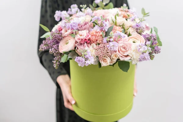 Tienda floral europea. Ramo floral en caja redonda. Ramo de hermosas flores mixtas en mano de mujer. Excelentes flores de jardín en el arreglo, el trabajo de un florista profesional . — Foto de Stock