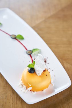 Sarı mus-kek. Fransız tatlısı, yaban mersini, nane ve beyaz tabakta bir parça beze. Şık bir şekilde dekore edilmiştir. Restoran menüsü